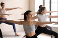 Indian girl and a group practicing yoga, doing Warrior II Royalty Free Stock Photo