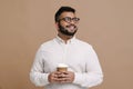 Indian guy holdiing cup of coffee isolated over beige background