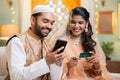 Indian happy smiling muslim couple making online payment for shopping using credit card on mobile phone during ramadan Royalty Free Stock Photo