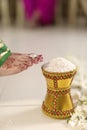 Indian Hindu Bride entering groom's home after wedding by pushing pot filled with rice with her foot. Royalty Free Stock Photo