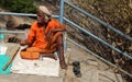 Indian Hindu senior man seeks help or alms or begs on stairs of temple