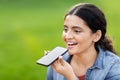 Indian lady dictating to phone on green field