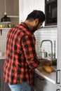 Indian or latino man cooking breakfast while standing at the kitchen at home, rear view Royalty Free Stock Photo