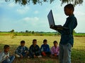 an indian little boy giving training about laptop computer system at natural background in india January 2020