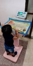 An indian little boy standing upon weight machine at hospital