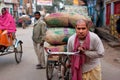 Indian loader works hard and carries bags of cargo on an old bicycle