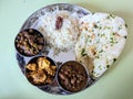 Indian lunch served in a traditional silver plate with naan rajma paneer mushroom peas curry and zeera rice