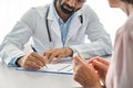 Indian male doctor consulting senior old patient filling medical form. Royalty Free Stock Photo
