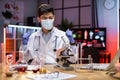 Indian male doctor microbiologist using microscope with vacuum tubes