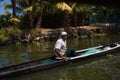 An Indian male fisherman on a traditional wooden boat sails through a channel overgrown with algae Royalty Free Stock Photo