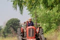 An Indian male senior farmer plowing the field with the help of a tractor plow Royalty Free Stock Photo