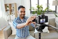 Indian male video blogger adjusting camera at home