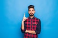 Indian man with beard raising index finger up while having brilliant idea isolated on blue background Royalty Free Stock Photo