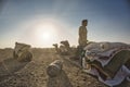 Indian man cameleer camel driver with camels in dunes of Thar desert