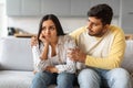 Indian man comforting his distressed girlfriend while sitting together on sofa