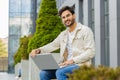 Indian man freelancer start working opens laptop sends messages reading email outdoors on bench Royalty Free Stock Photo