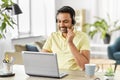 Indian man with headset and laptop working at home