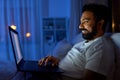 indian man with laptop in bed at home at night Royalty Free Stock Photo