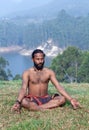 Indian man meditating in lotus yoga pose on green grass Royalty Free Stock Photo