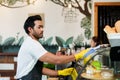 Indian man owns family\'s small coffee shop, helping wife clean the glass cupboard that holds the cakes. and preparing Royalty Free Stock Photo