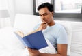 Indian man reading book in bed at home Royalty Free Stock Photo