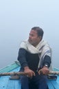 Indian man sailing on the boat on sacred river Ganges at cold foggy winter morning Royalty Free Stock Photo