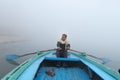 Indian man sailing on the boat on sacred river Ganges at cold foggy winter morning Royalty Free Stock Photo