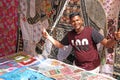 Indian man salesman in the Anjuna market, Goa, India. Indian markets, trade. A store of shawls and stoles