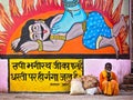 Indian Man Sitting By Colorful Hindu Art in Varanasi, India