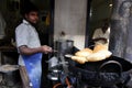 Indian man is standing fried puri, which is Indian food. With a large black pan. But use the oil used to fry. In a restaurant in t