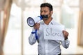 Indian man with taped mouth holding poster with inscription Silence. Royalty Free Stock Photo