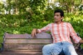 Indian man thinking while sitting on wooden bench in peaceful gr Royalty Free Stock Photo