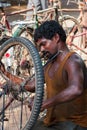 An Indian man uses a spanner to tighten the on the wheel o