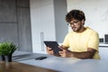 Indian man using digital tablet white sitting in the kitchen Royalty Free Stock Photo