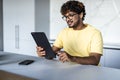 Indian man using digital tablet white sitting in the kitchen Royalty Free Stock Photo