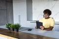 Indian man using digital tablet white sitting in the kitchen Royalty Free Stock Photo