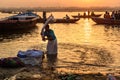 Indian man washing clothes in holy water of river Ganga in sunrise. Varanasi. India Royalty Free Stock Photo