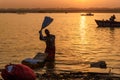 Indian man washing clothes in holy water of river Ganga in sunrise. Varanasi. India Royalty Free Stock Photo