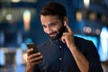 Indian man wearing earbud having video call on cell phone outdoors.