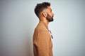 Indian man wearing elegant sweater and sunglasses standing over isolated white background looking to side, relax profile pose with Royalty Free Stock Photo