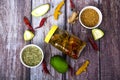 Indian mango pickle with green mango slices and spices with brown bowl on wooden background