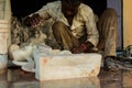 An Indian Marble Sculptor is sculpting a local Hindu deity with the help of modern grinding tool