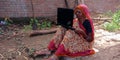 An Indian matured women using laptop seating at farmers field