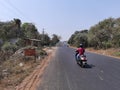 Indian men going on scooter on road in village