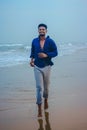 Indian men model running on beach sand in sea view background. Handsome and confident men. Outdoor portrait of running young Asian Royalty Free Stock Photo