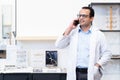 Indian middle aged ophthalmologist or optometrist man work at optometry clinic, using mobile phone appointing patient to check Royalty Free Stock Photo