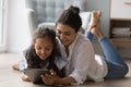 Indian mom and little daughter lying on floor using tablet Royalty Free Stock Photo