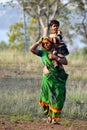 An Indian mother carrying her daughter on her shoulder