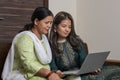Indian mother and daughter watching into the laptop at home. Modern daughter helping her mother with technology. Mother and Royalty Free Stock Photo