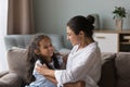 Indian mother playing with preschooler daughter seated on sofa